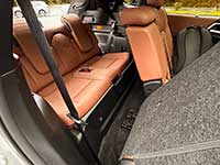2026-Outlander-PHEV-seating - Warman Voice Cargo area of a car with orange-brown leather rear seats folded down, gray carpeting, and a visible seat belt.